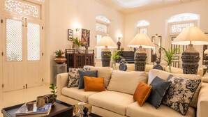Uma sala de estar espaçosa com um sofá bege, luminárias decorativas e uma mesa de centro com livros e um vaso.