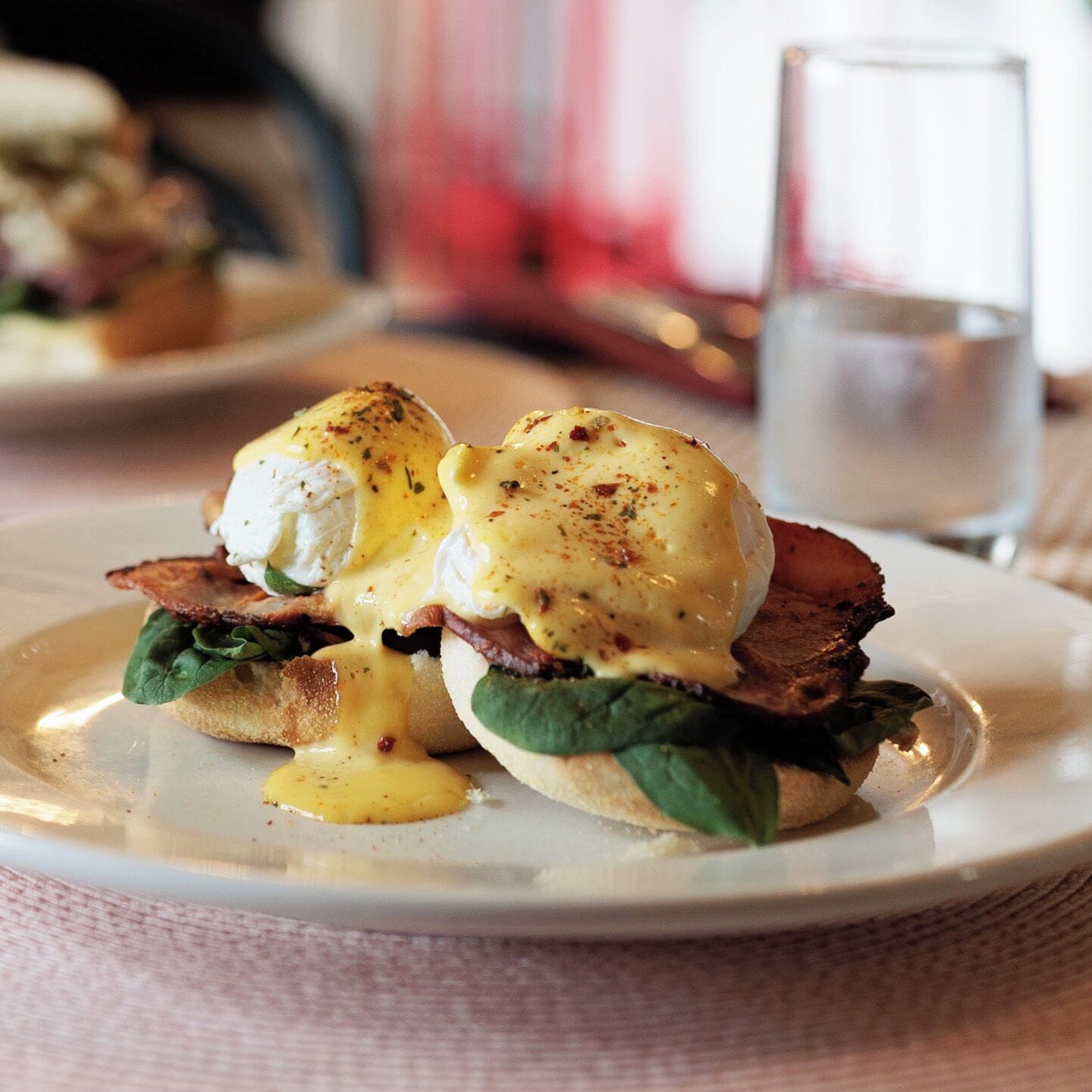 A breakfast dish with eggs, bacon, and greens on a plate.