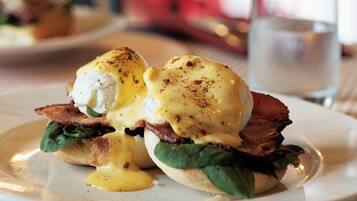 A breakfast dish with eggs, bacon, and greens on a plate.
