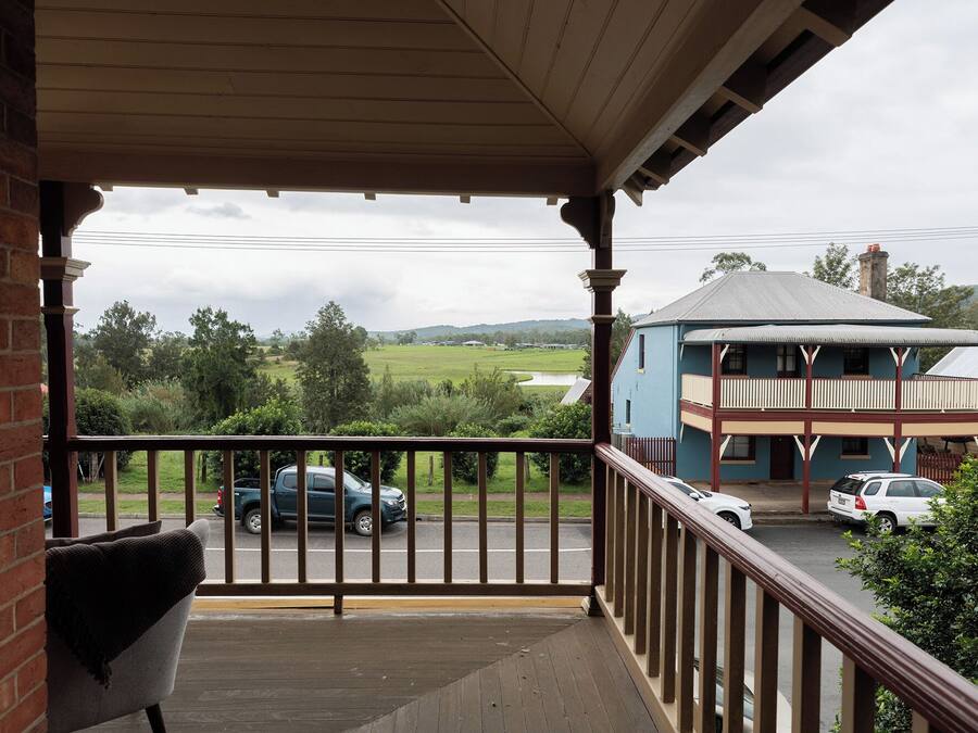 A balcony with a view of a road and a building across it.