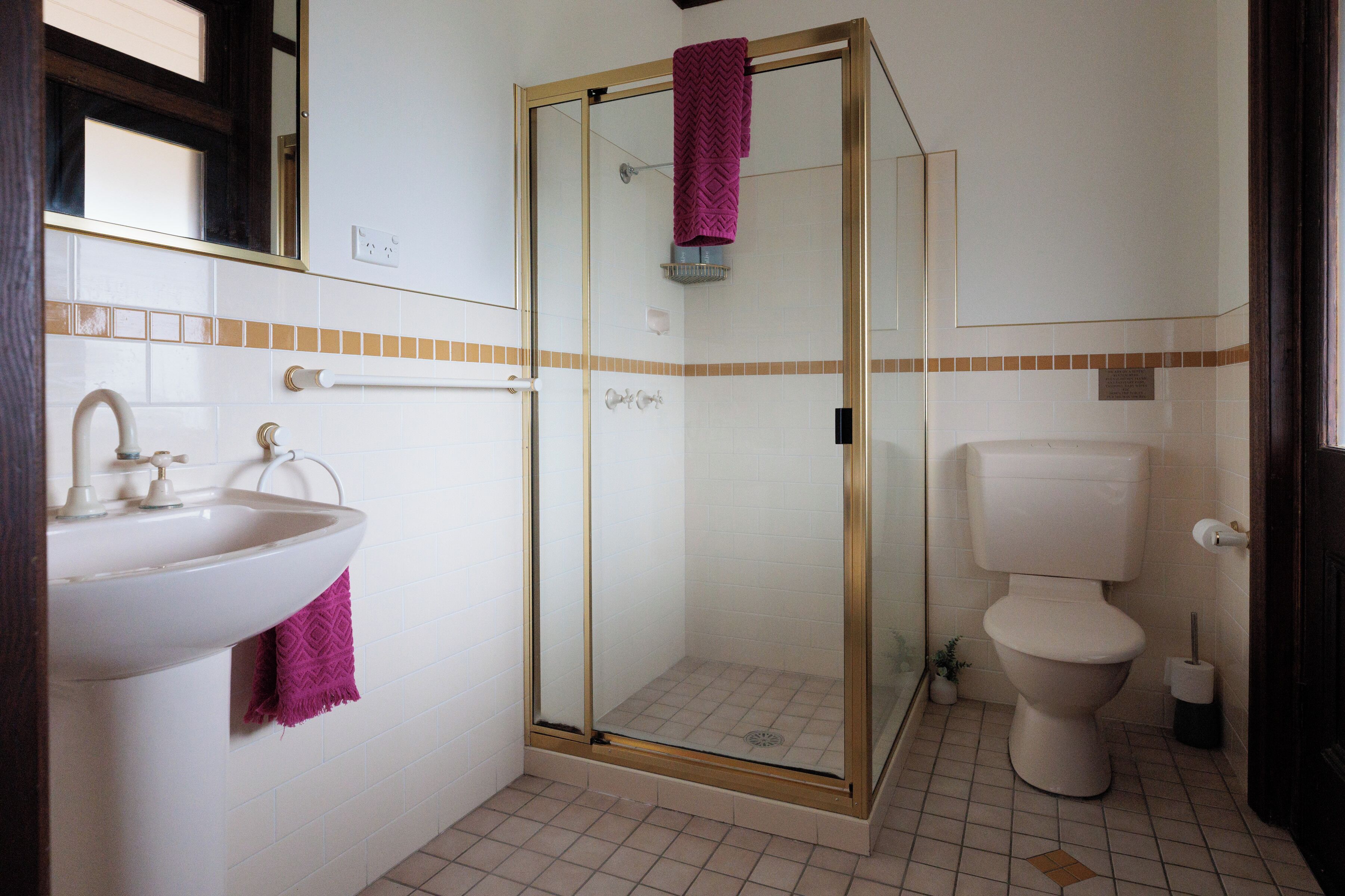 A bathroom with a glass-enclosed shower, a sink with a towel, and a toilet.