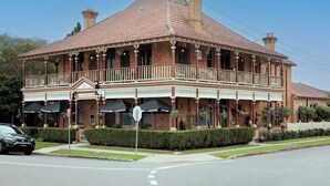 A two-story brick building with a balcony, multiple windows, and outdoor umbrellas. - Kings and Queens Paterson (Paterson)
