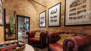 A cozy room with leather sofas, a brick wall, and framed historical photos. - Kings and Queens Paterson (Paterson)