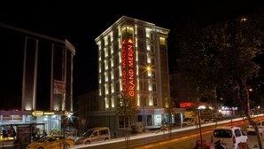 A hotel with a prominent 'GRAND MERIT' sign, a modern facade, and a busy street with vehicles and pedestrians. - Grand Merin Airport Hotel (Istanbul)