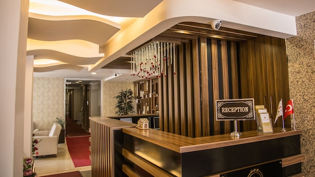 A reception area with a wooden reception desk, a sign reading "RECEPTION", and a security camera above the desk. - Grand Merin Airport Hotel (Istanbul)