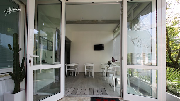 Un intérieur moderne avec une porte vitrée donnant sur un coin repas, où l’on trouve des chaises blanches et une table.