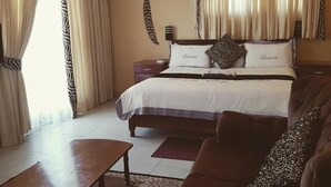 Una habitación de hotel con una cama, un sofá, una mesita de café y cortinas.