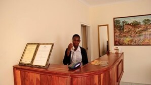 Mostrador de recepción con detalles de madera, un teléfono y certificados enmarcados a la izquierda.