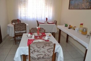Comedor con dos mesas dispuestas para comer, sillas y una barra con aderezos.