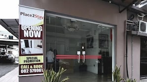 A hotel entrance with a glass door, a banner advertising a special promotion, and a contact number.