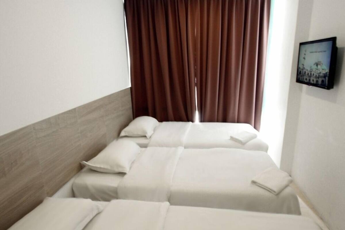 A hotel room with two single beds, a wooden headboard, brown curtains, and a framed picture on the wall.