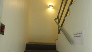 A staircase with a handrail and a light fixture above it. There is a sign on the wall to the right of the stairs.