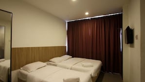 A hotel room with two beds, a wooden headboard, a large mirror, and a dark curtain.