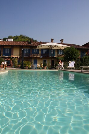 Una piscina al aire libre de temporada, sombrillas, tumbonas