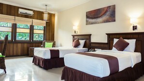 A hotel room with two beds, a wooden headboard, a wall-mounted air conditioner, a large window with a view of greenery, and a painting on the wall. - Arsela Hotel Pangkalan Bun (Pangkalan Bun)