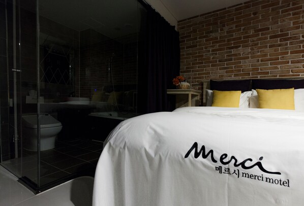 Una habitación de hotel con una cama, un baño y una pared de ladrillo.