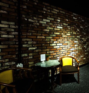 A brick wall with a table and chairs, a potted plant, and a sign. - Hotel Merci (Iksan)