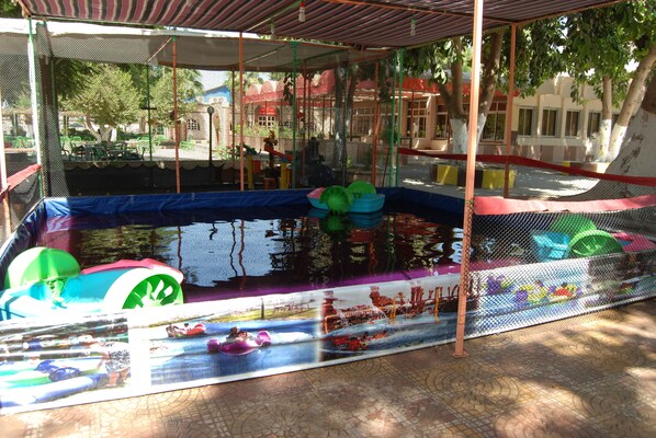A covered swimming pool with inflatable toys and a safety net.