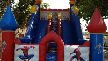 Un castillo inflable con temática de Spider-Man, que incluye un tobogán y una entrada en forma de arco.