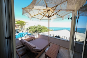 Een balkon met een bed, een tafel en een parasol.