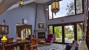 Uma sala de estar ampla com lareira, janelas grandes e vista para o jardim.