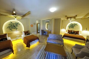 Habitación de hotel con dos camas, un sofá, una silla, un espejo y ventiladores de techo.