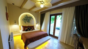 Quarto com cama, abajures, ventilador de teto, radiador e vista para o exterior através de uma janela.