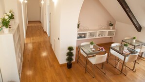 Una cocina moderna con armarios blancos, suelo de madera y una mesa de comedor de cristal con sillas blancas.