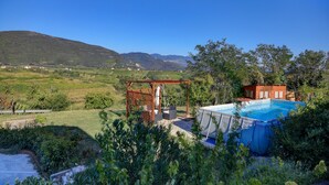 A pool area with a pergola and a small building, surrounded by greenery and hills. - Dal Rosso (San Floriano del Collio)