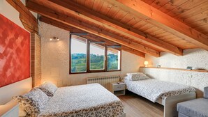 A bedroom with two beds, a wooden ceiling, and a view of the countryside. - Dal Rosso (San Floriano del Collio)