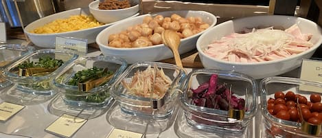 Un bufé con diversas opciones de comida, como pollo, pepinillos y vegetales.