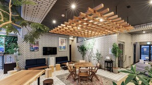 Un interior moderno con pared de ladrillo, techo de madera y zona de comedor central con sillas y una mesa.