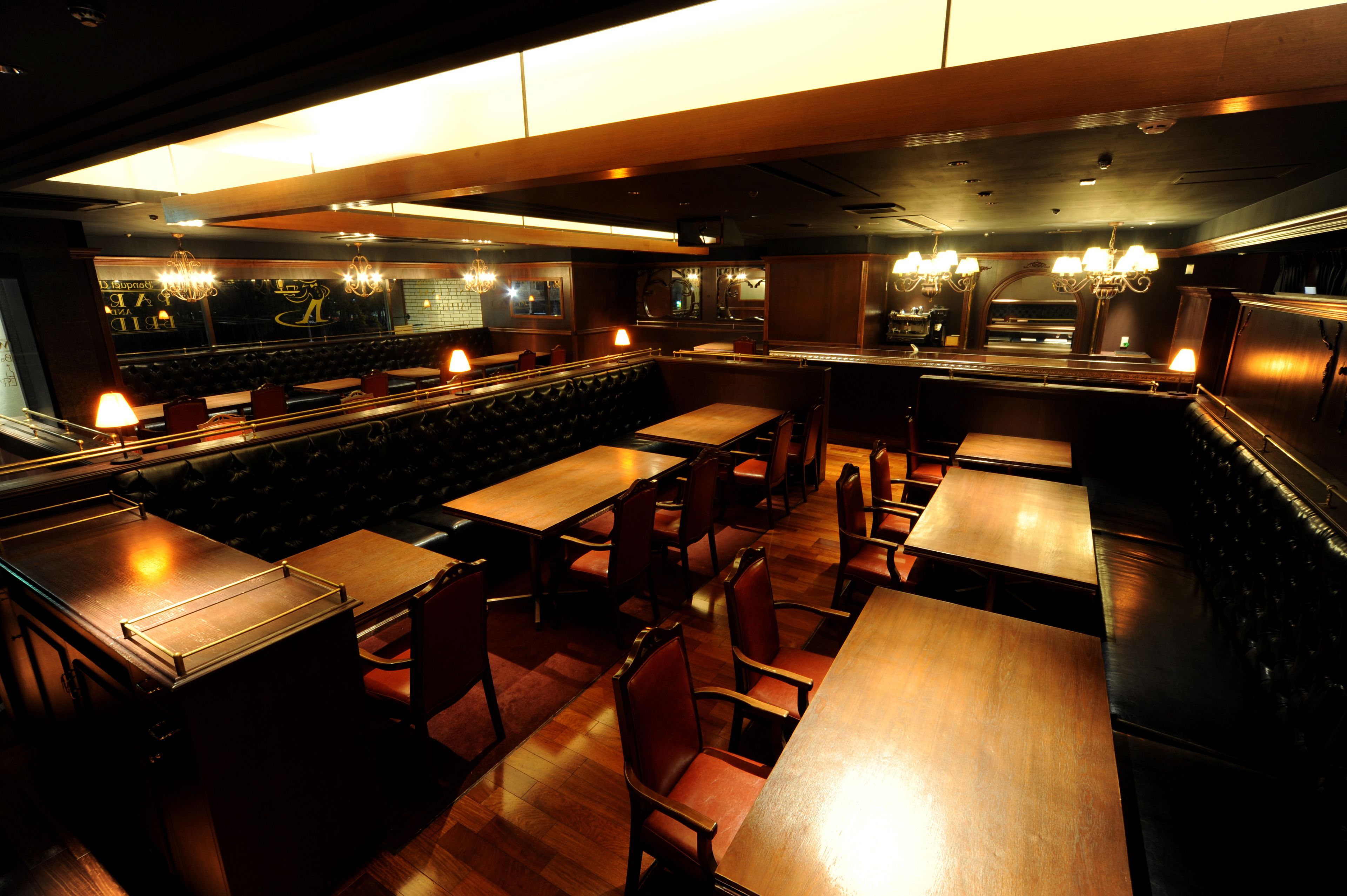 Un restaurant avec des banquettes et des tables, un plancher en bois et des lustres.
