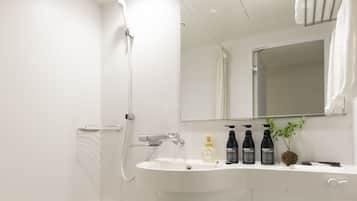 A modern bathroom with a bathtub, a sink, and a toilet. There are three bottles of shampoo on the sink counter.
