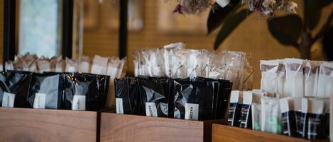 A display of packaged products on wooden shelves, with hanging dried flowers and a light bulb in the background.