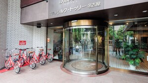 La entrada del Hotel Silk Tree con una puerta giratoria, fachada de vidrio y una fila de bicicletas rojas afuera.