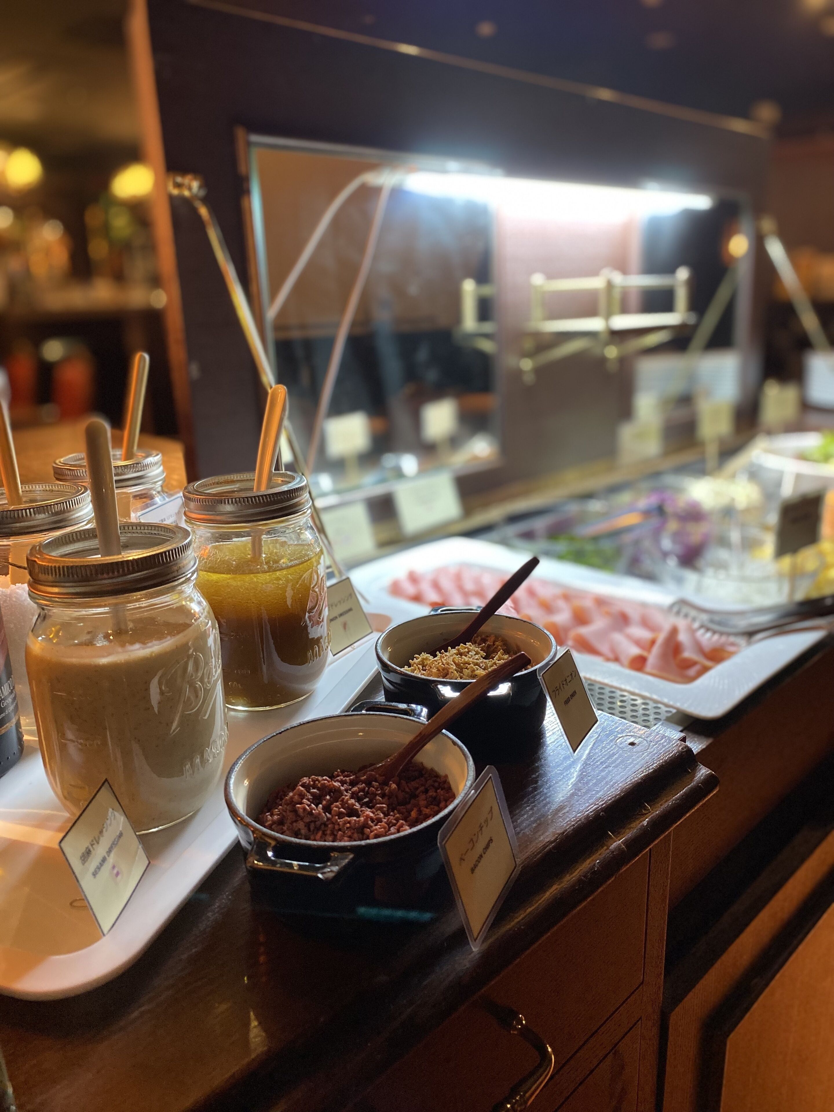 A buffet with various food items, including jars of sauces, bowls of rice, and a selection of meats.