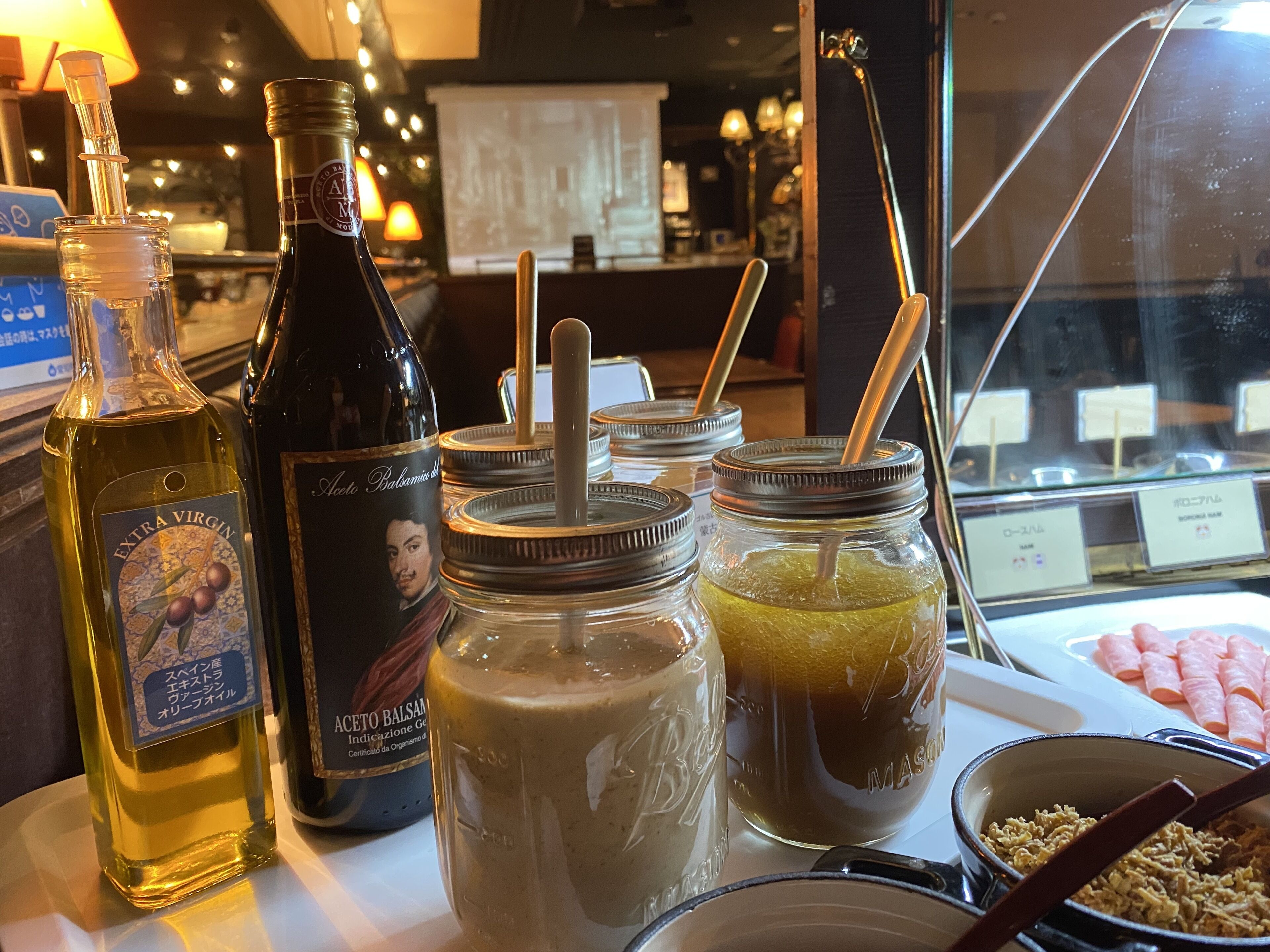 Una mesa con una botella de aceite de oliva extra virgen, una botella de vinagre balsámico y dos frascos de vidrio con pajitas.