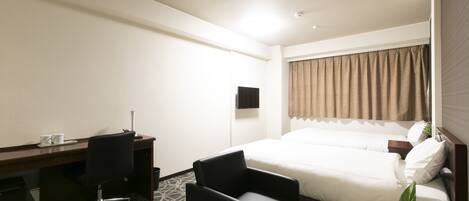A hotel room with a bed, a desk, a chair, a small table with a plant, and a TV on the wall.