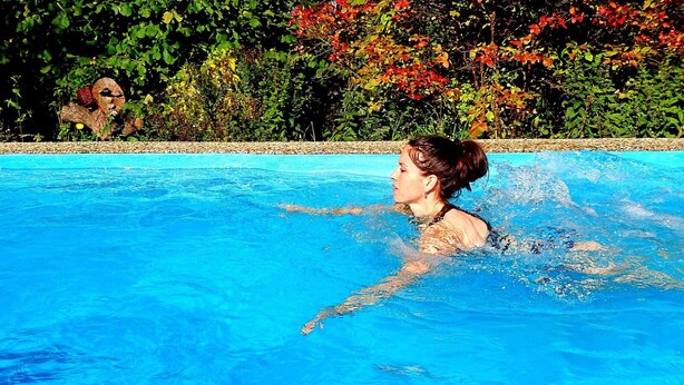 Une personne nage dans une piscine dont les bords sont recouverts de petits galets.