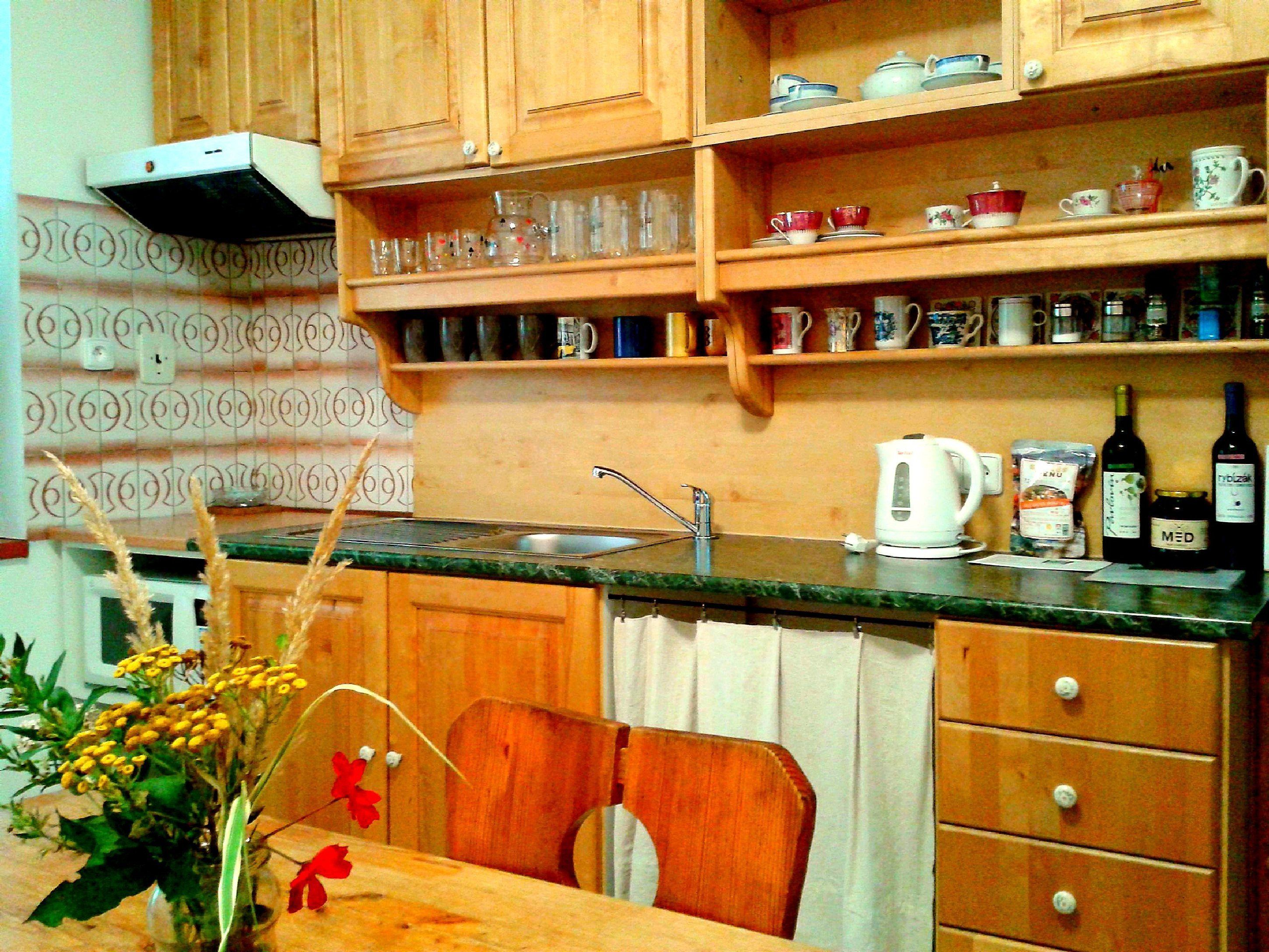 A kitchen with wooden cabinets, a marble countertop, a sink, and a dining area with a chair and table.