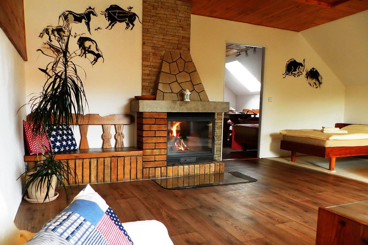 Una sala de estar con chimenea, piso de madera, un banco y una cama.