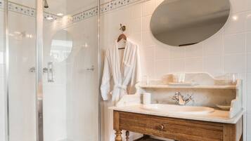 Een moderne badkamer met een douchecabine van glas, een houten wastafelmeubel met een marmeren blad en een grote spiegel.