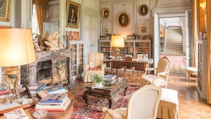 A spacious library with bookshelves, a fireplace, and comfortable seating areas. - Château de Boucéel (Saint-James)