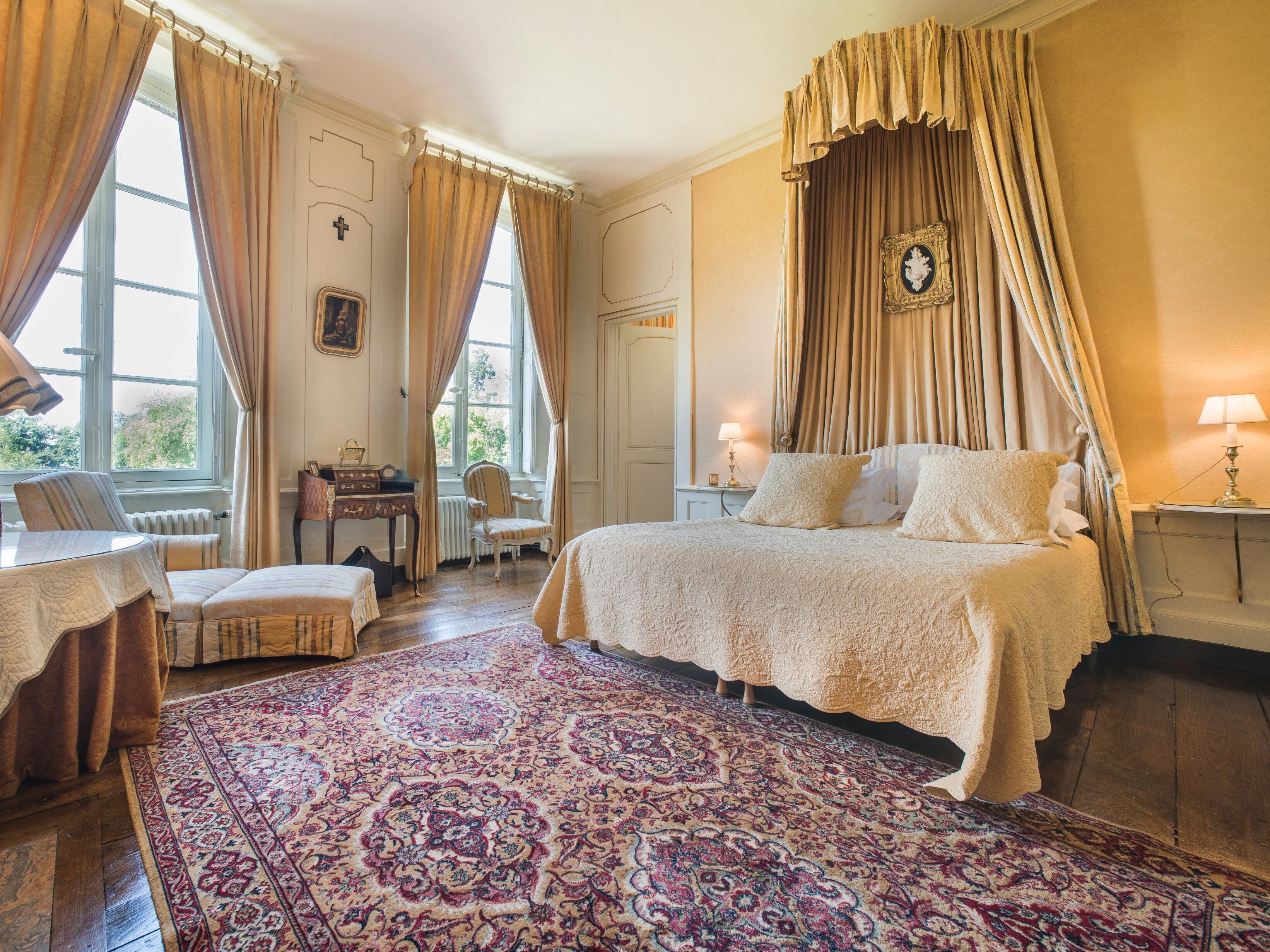 Une chambre spacieuse avec un grand lit, un coin salon comprenant une chaise et une table, et une vue sur l’extérieur par une fenêtre.