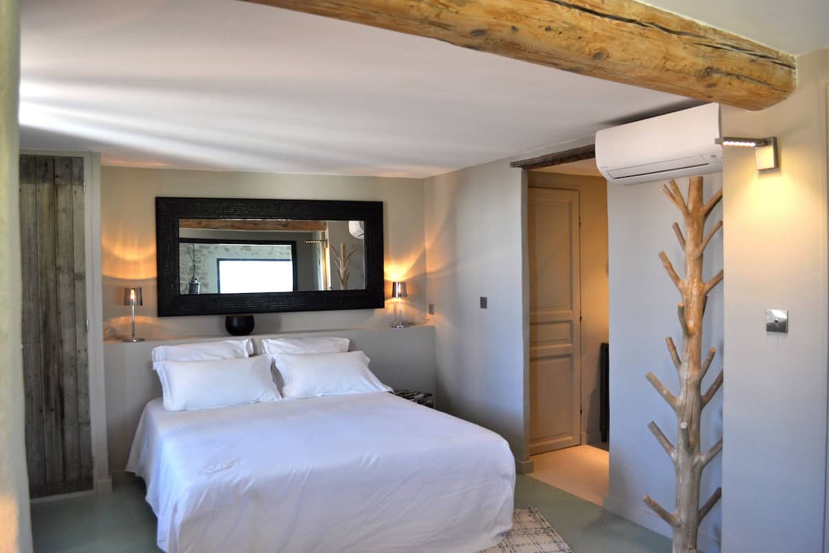Ein Schlafzimmer mit einem großen Bett, einem Spiegel und einer Holzskulptur eines Baumes.