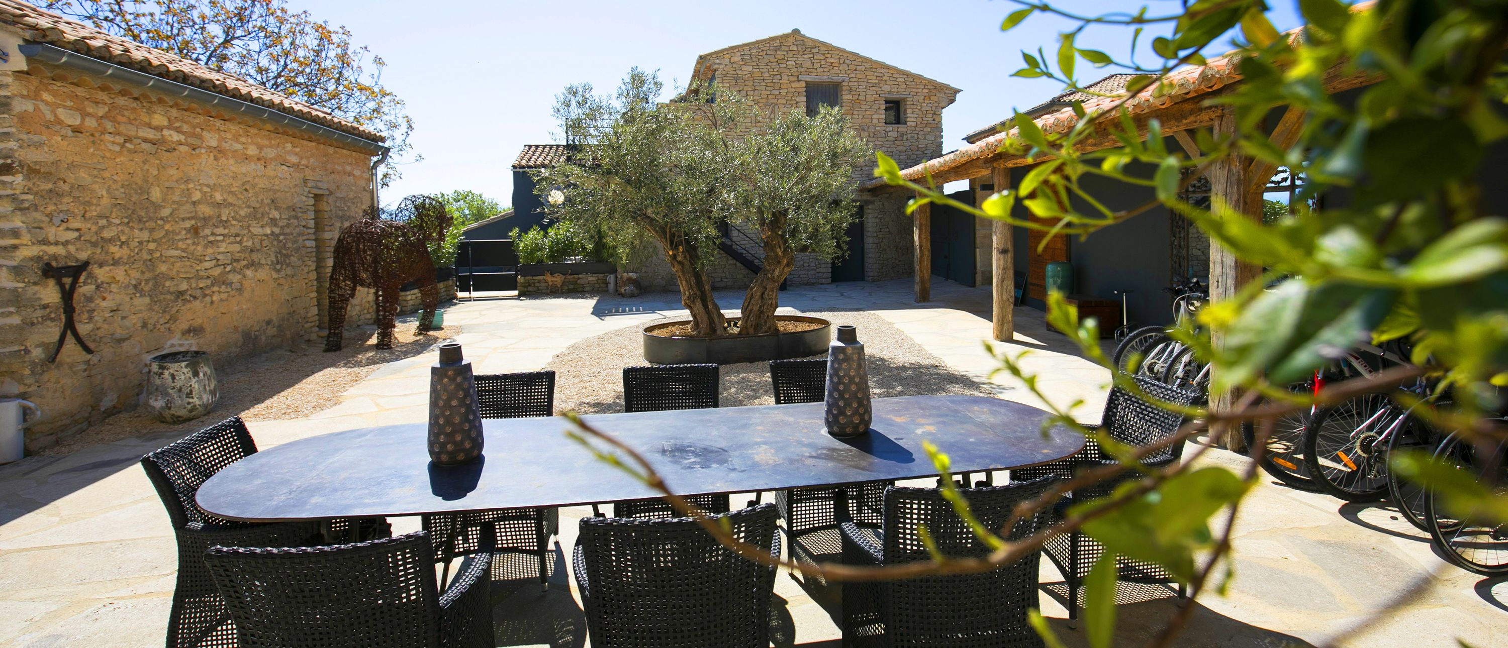 Eine Terrasse im Freien mit Tisch und Stühlen, umgeben von Steinmauern und einem Baum.