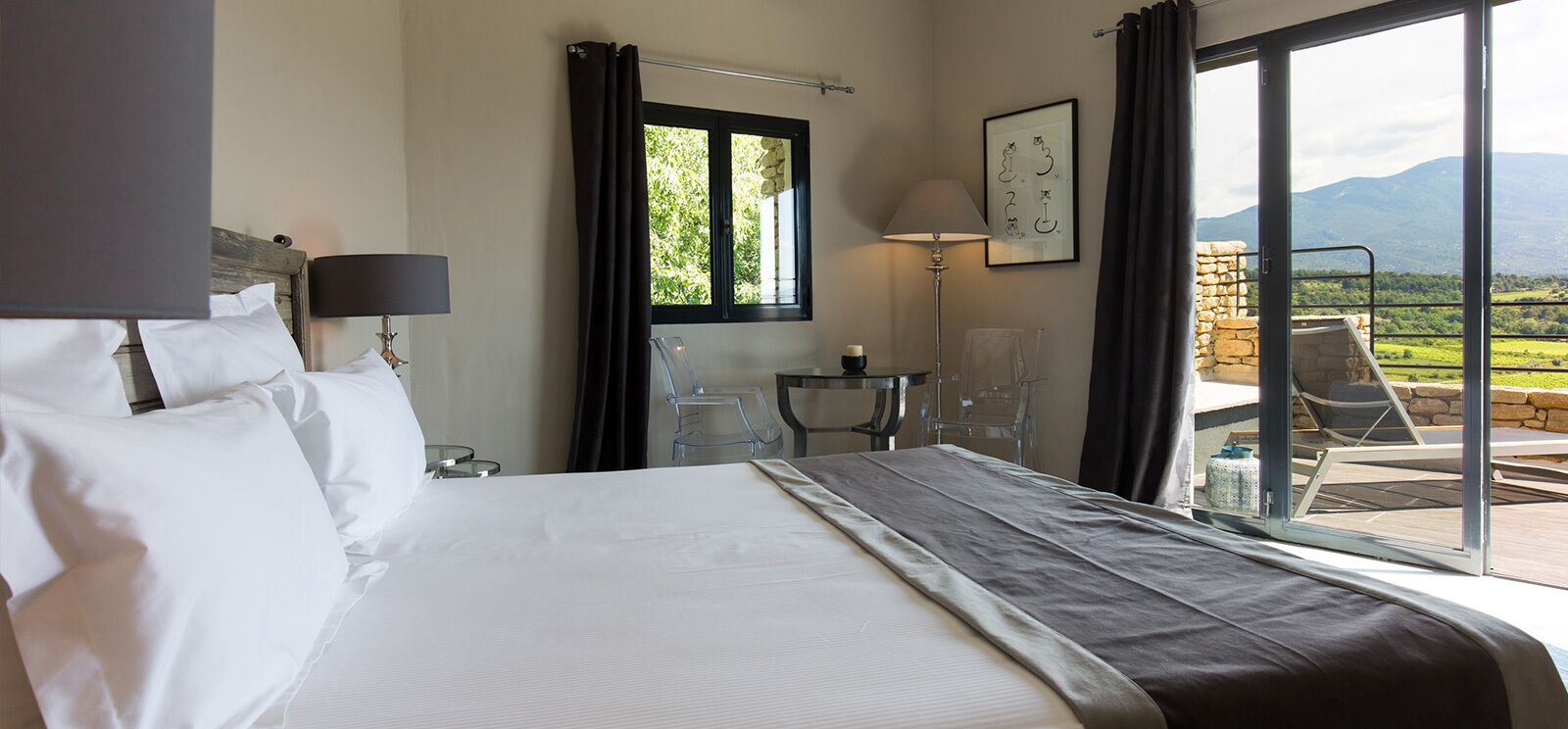 A hotel room with a bed, a desk, a chair, and a view of the outdoors.