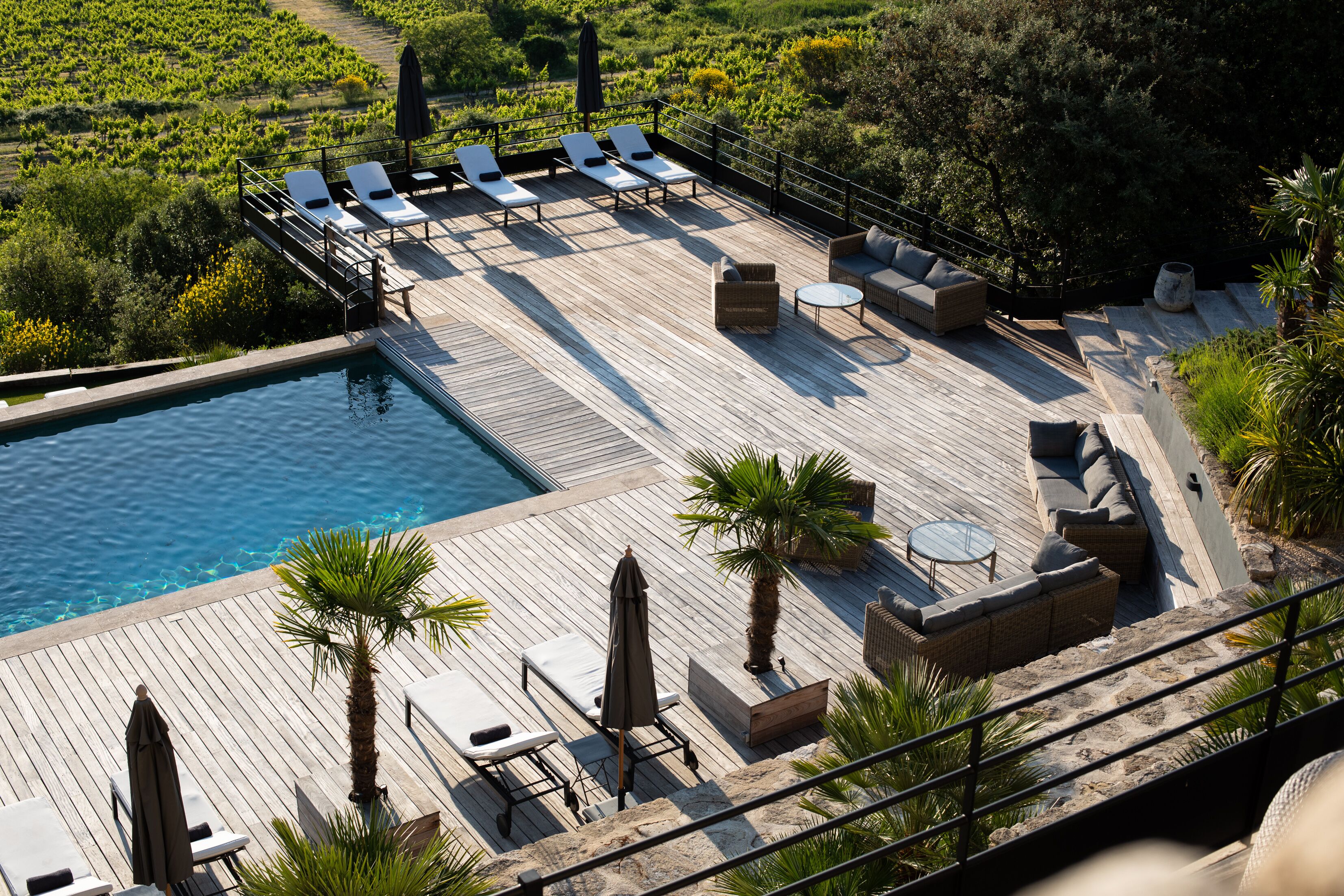 A rooftop pool area with lounge chairs, a small table, and a sofa.