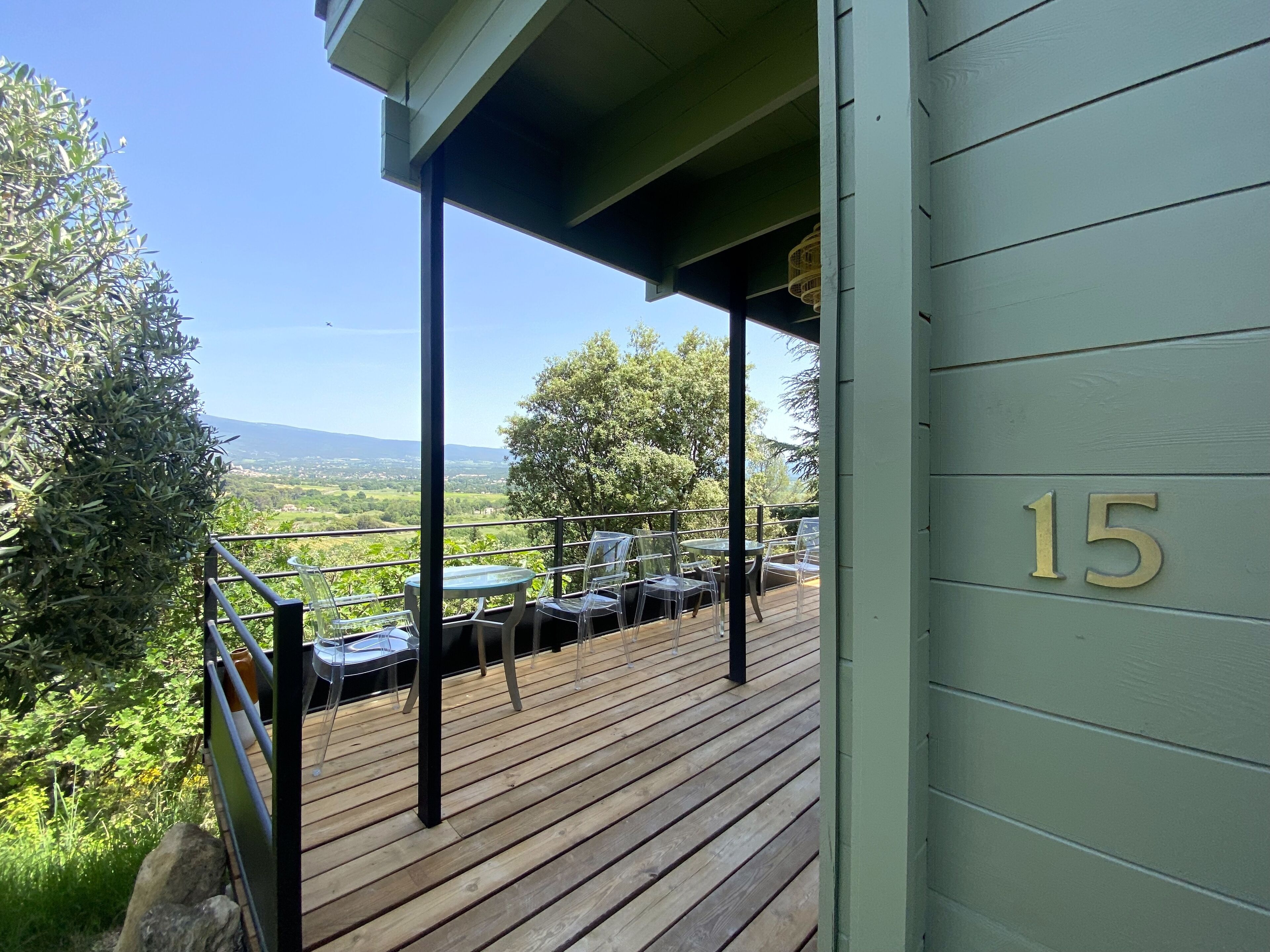 Una terraza de madera con mobiliario exterior, con vistas a un paisaje pintoresco.